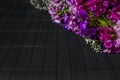 Diagonal frame of purple and violet flowers on dark wooden background, floral black background boards, copyspace Royalty Free Stock Photo