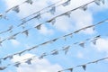 Diagonal garland of white flags of triangular shape, pennants against blue cloudy sky. City street holiday, Festival