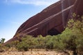 Diagonal picture of red wall at Mount Uluru mountain.Cave carved on the all due to water erosion. Green trees. Sacred Mount Uluru