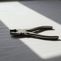 Diagonal pliers with black, textured handles rest on a white surface, partially illuminat Royalty Free Stock Photo