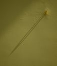 A diagonal shadow of a hook on the yellow wall