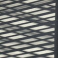 Diagonal shadow patterns are cast on a surface, creating a repeating geometric Royalty Free Stock Photo