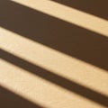 Diagonal shadows are cast on a textured beige surface, likely created by sunlight Royalty Free Stock Photo