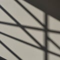 Diagonal shadows create an abstract pattern on a light textured surface. The