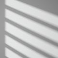 Diagonal shadows of evenly spaced horizontal lines are cast on a smooth, white Royalty Free Stock Photo