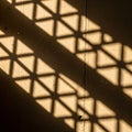 Diagonal shadows with triangular patterns are cast on a beige concrete Royalty Free Stock Photo