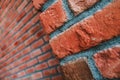 Diagonal side angle of a red brick wall corner. Close up view of cracked weathered brickwork material. Modern interior design,