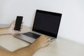 Diagonal view of a home workspace with computer on, left hand with smartphone and right hand typing.