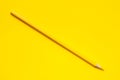 Diagonal yellow sharp wooden pencil on a bright yellow background, isolated, copy space, mock up