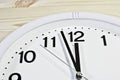 Dial of an analog clock close up on a wooden background. The time is 23:59. White dial, black numerals Royalty Free Stock Photo