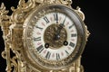 Dial of vintage bronze clock on black background, antique clock photo close up, old bronze clock in gilding, the first hour on the Royalty Free Stock Photo