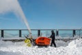 Dialerets, Valais / Switzerland -21.10.2020: Man in black with a red snow blowing machine working in winter day beside glass