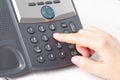 Dialing voip phone in the office, keyboard and monitor detail in the background