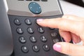 Dialing voip phone in the office, keyboard and monitor detail in the background