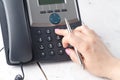 Dialing voip phone in the office, keyboard and monitor detail in the background