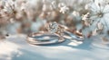 Diamond engagement ring nested with a wedding band among blooms. Elegant bridal rings set against soft white flowers. Wedding and Royalty Free Stock Photo