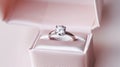 A diamond engagement ring in a pink ring box on a blurred pink background. The ring has a round diamond on a white gold Royalty Free Stock Photo