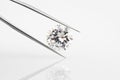 Diamond held in tweezers on grey background. Royalty Free Stock Photo