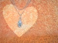 Diamond pendant and white gold necklace on an olded rose color heart carpet background. Use to with love in every festival. Royalty Free Stock Photo