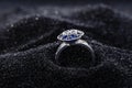 Diamond Shape Silver Ring With Blue Gemstones On Black Sand.