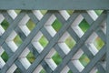 Diamond-shaped wooden lattice painted white against the background of a green lawn Royalty Free Stock Photo