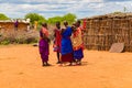 Maasai women in traditional dress communicate with each other and laugh