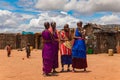 Maasai women in traditional dress communicate with each other and laugh