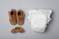 Diaper and baby accessories on grey background, flat lay