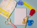 diaper, pacifier, comb, scissors and a notepad with a pen