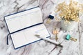 A diary with a white pen and paper clips on a marble table and white flowers. Notebook for business records for a week Royalty Free Stock Photo