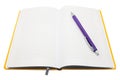 Diary in yellow cover with a purple ballpoint pen in the middle on a white background Royalty Free Stock Photo