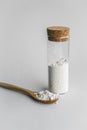Diatomaceous earth also known as diatomite mixed in glass jar and wood spoon on gray background studio shot.