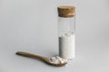 Diatomaceous earth also known as diatomite mixed in glass jar and wood spoon on gray background studio shot.