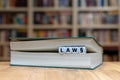 Dice in a book form the word `LAW `. Book is lying on a desk in a library. Royalty Free Stock Photo