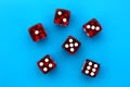 Six red dice lie on an isolated blue background.