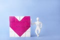 dice heart. beside him, leaning, stands a man of white plasticine. blue background.