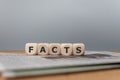 Dice placed on a newspaper form the word `facts`