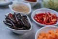 Diced carrots, dried chilies, roasted rice, and chili paste on a cement floor