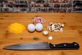 Diced Mushrooms and ham with cheese and eggs, salt, pepper and dill, on a wooden cutting surface with a knife