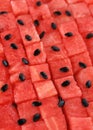 Diced red ripe watermelon in rows, black seeds are scattered on top. Juicy fresh fruit vertical background. Royalty Free Stock Photo