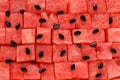 Diced red watermelon laid out in even rows, black seeds are scattered on top. Juicy fresh fruit pieces background. Royalty Free Stock Photo