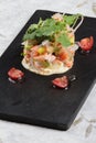 Diced salmon salad with avocado, tomato, onion, chilli, and coriander served in black rectangle stone plate on washi.