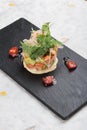 Diced salmon salad with avocado, tomato, onion, chilli, and coriander served in black rectangle stone plate on washi.