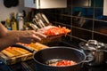 DICED TOMATOES AND ONIONS BEING COOKED IN FRYING PAN ON OVEN.