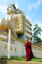 Dickwella, Sri Lanka, 04-15-2017: Buddhist monk holds mobile phone in hands of Buddhist temple on the background of Buddha statue Royalty Free Stock Photo