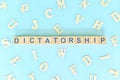 Dictatorship government form concept. Wooden blocks typography flat lay in blue background.