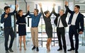 We did it again team. a confident looking team of coworkers sheering together while standing in a modern office. Royalty Free Stock Photo