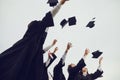 Group of graduate students in gowns throw square academic hats in the air at graduation. Royalty Free Stock Photo