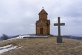 Didgori battle memorial, Georgia. Winter and snow, overcast. The small church is built of orange bricks with a cross on the dome.