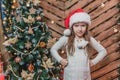Disappointed little girl wearing Christmas costume standing isolated over wooden christmas background, keeping arms Royalty Free Stock Photo